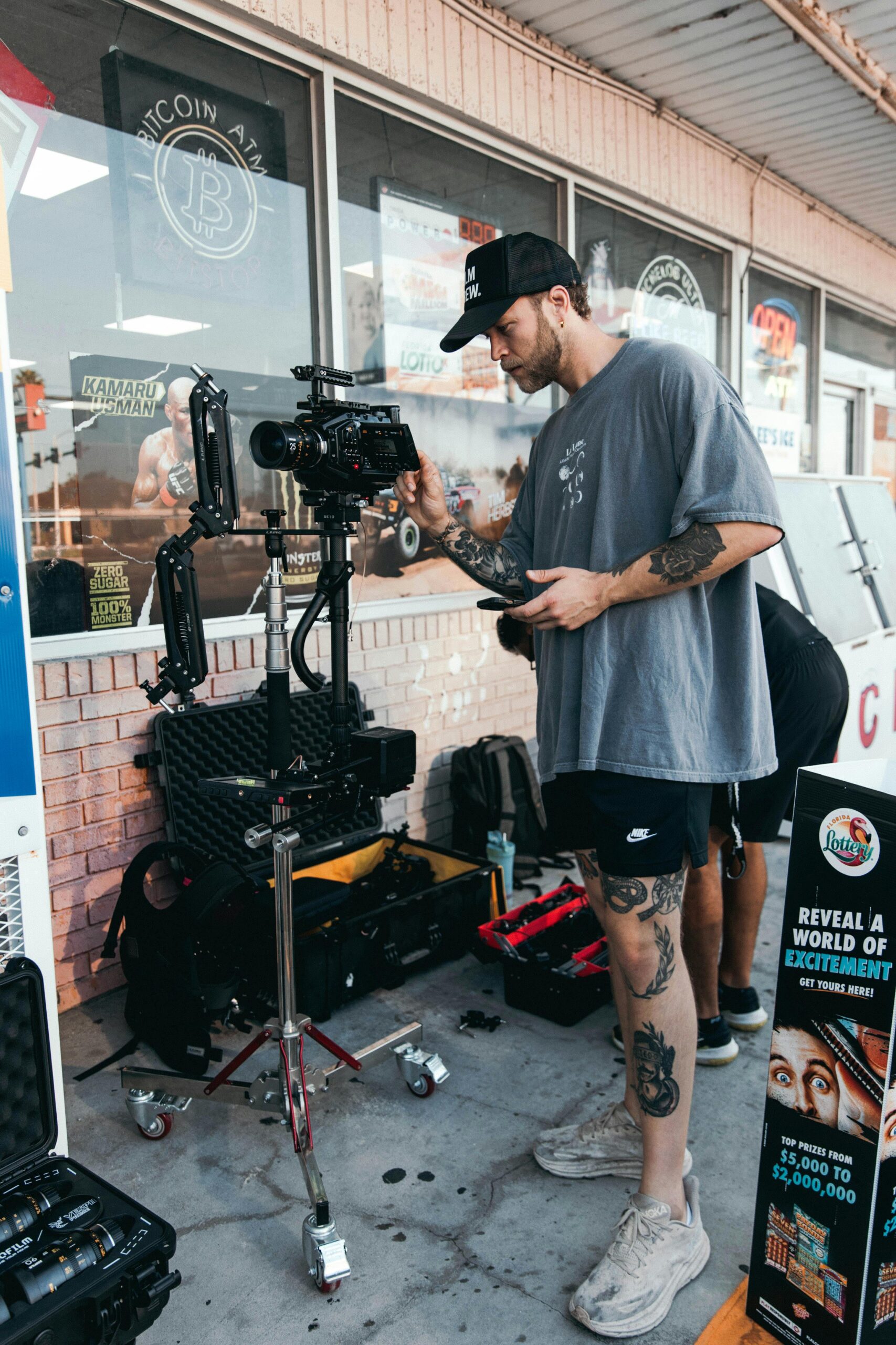 Videographer setting up camera gear outside a shop, capturing a scene.